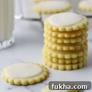 A stack of Nordic Lemon Wafers on a marble surface next to a glass of milk.