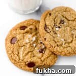 Close up of Rye Chocolate Chip Cookies sprinkled with sea salt next to a glass of milk.