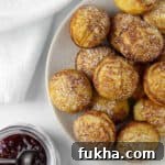 Close up of Danish Pancakes (æbleskiver) next to raspberry jam.