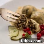Vegetarian Swedish meatballs on a plate with a fork lingonberries and a pickle.