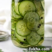 Quick Swedish Pickled Cucumbers in a jar next to peppercorns and fresh dill sprigs.