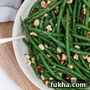 Green beans and hazelnuts in a bowl on a wood surface.