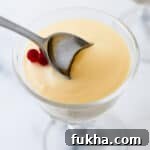 Close up of a spoon in a serving of Swedish Cream topped with lingonberries.