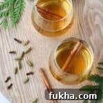 Cup of white mulled wine with cinnamon sticks and spices.