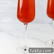 Champagne glass filled with Swedish 75 cocktail next to lingonberries.