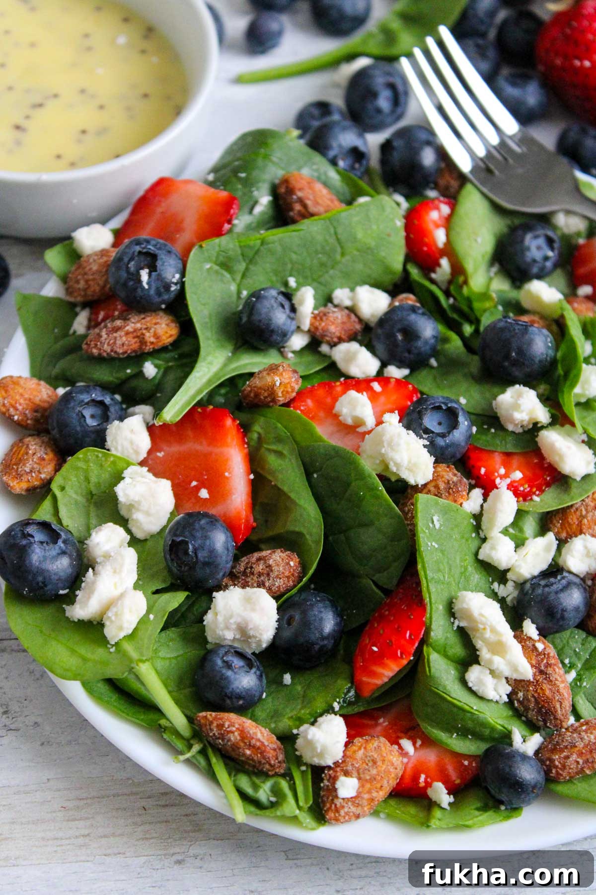 Assemble strawberry salad with feta cheese blueberries and spinach.