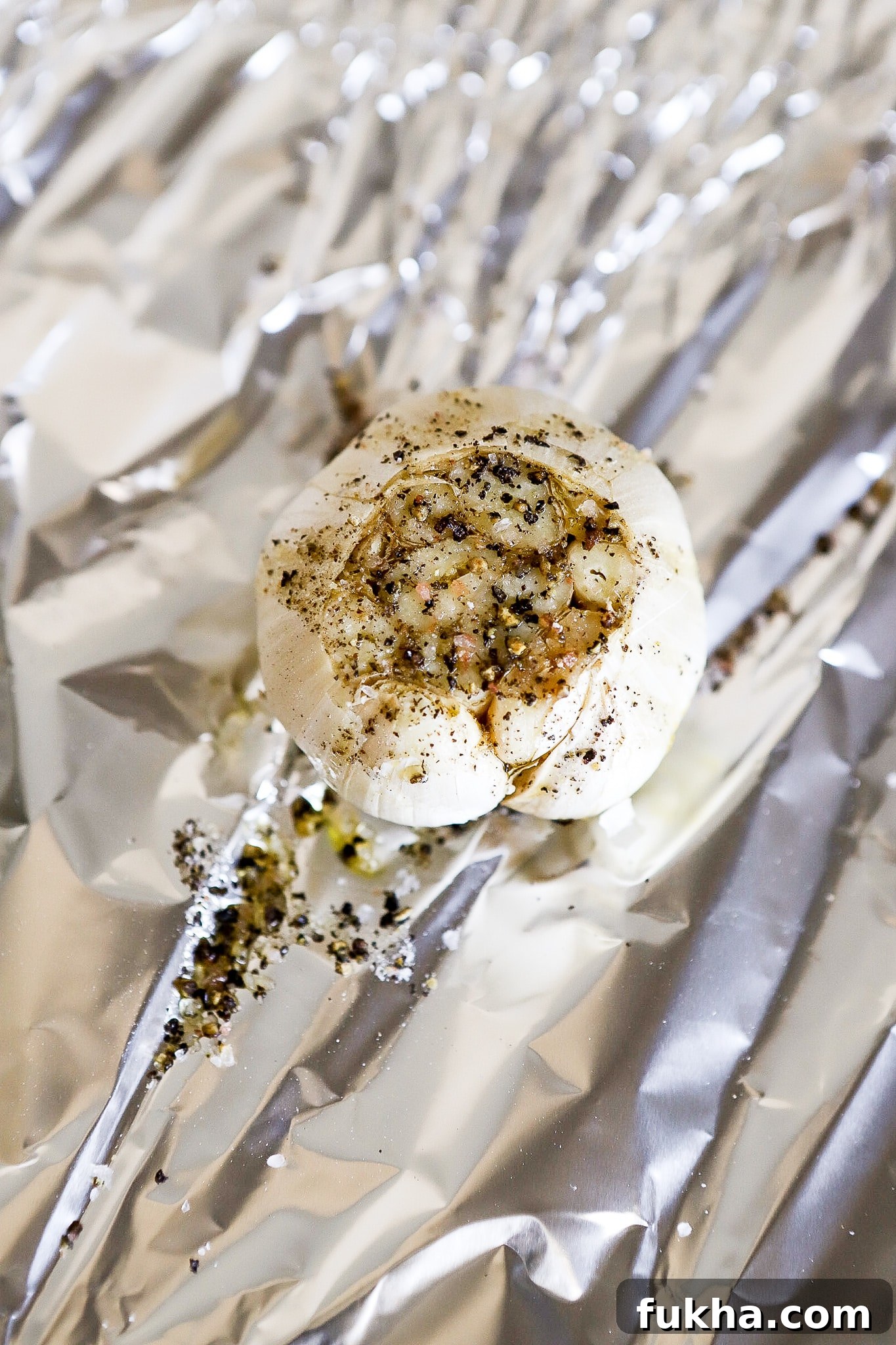 top down view of garlic bulb in aluminum foil with extra virgin olive oil ready for the air fryer